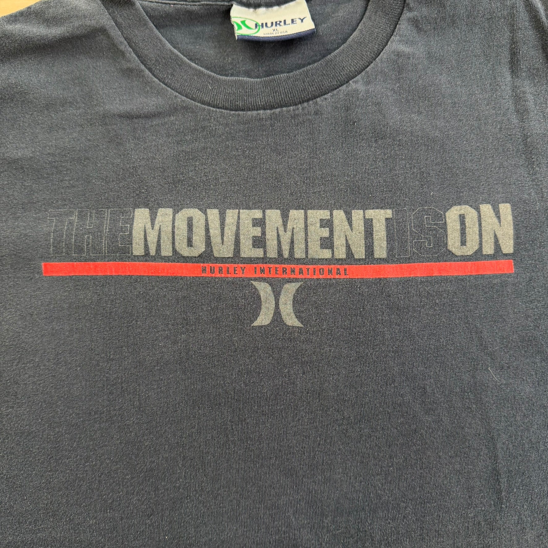 J- Vintage Hurley International The Movement Is On Graphic Text Made In USA Tee - XL